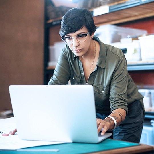 一个穿绿衬衫的黑发女人在储藏室里用笔记本电脑